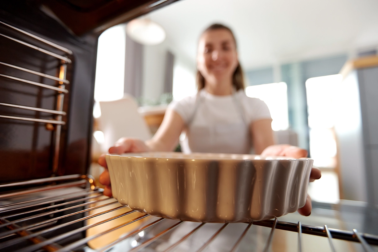 Frau schiebt eine Auflaufform in den Ofen